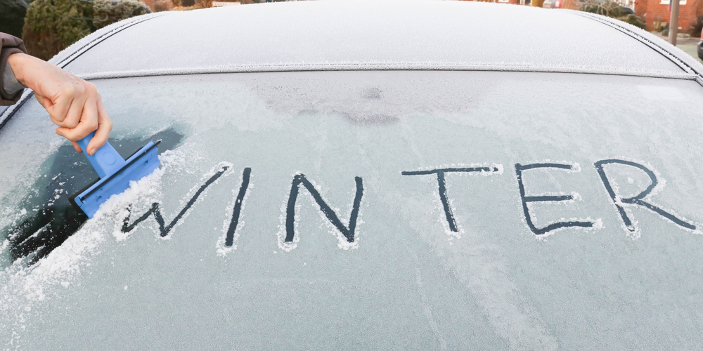 Scraping ice off windscreen in winter