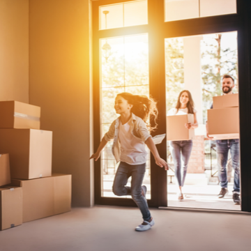 a happy family moving boxes into a house